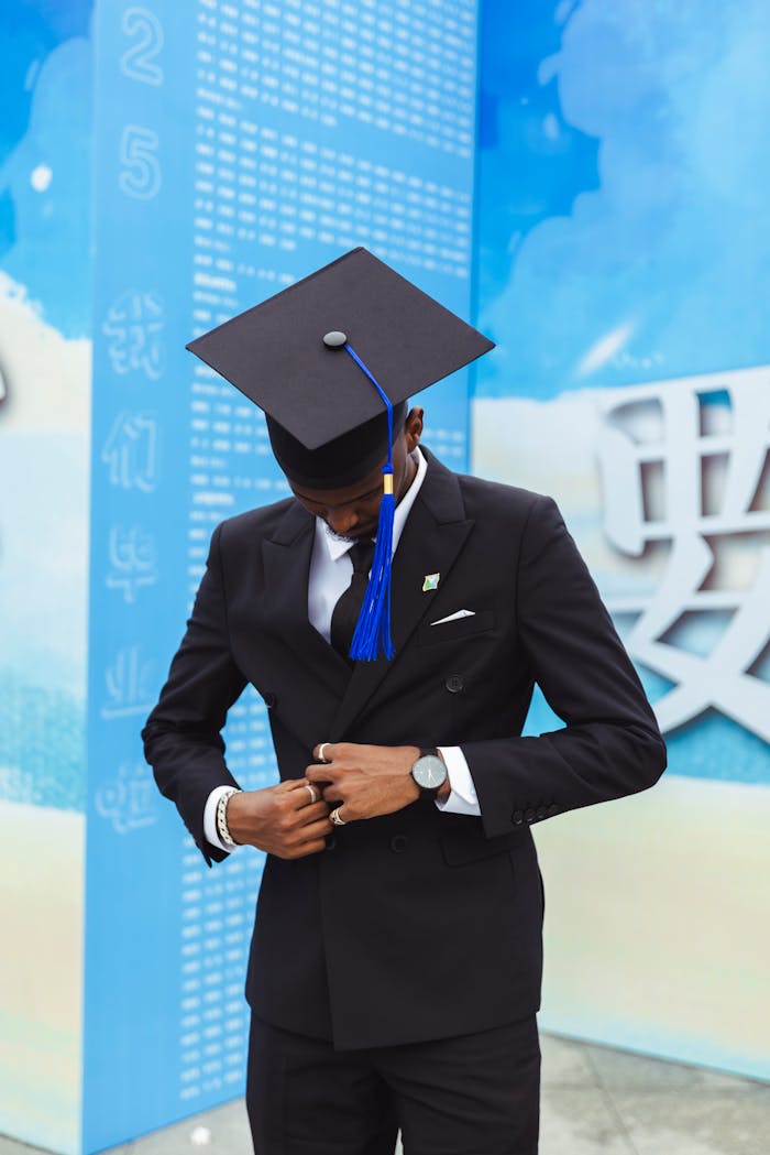 young-graduate-in-suit-with-cap-and-gown-celebrating-32703328